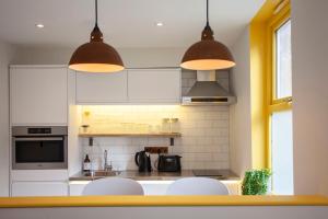 a kitchen with two white chairs and two lights at Higgihaus Aparthotel, Clare Street in Bristol