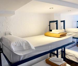 2 camas en una habitación con paredes blancas en Y Hostel - Albergue Juvenil en Palma de Mallorca
