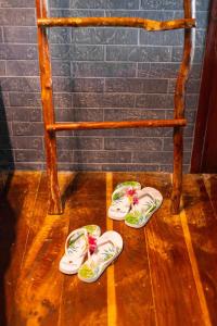 dois pares de chinelos no chão ao lado de uma cadeira em Vila de Taipa Exclusive Hotel em Japaratinga