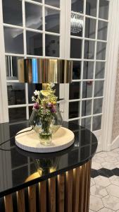 a glass table with a vase of flowers on it at Logis Hôtel Restaurant Grand Hôtel de Lyon in Vals-les-Bains