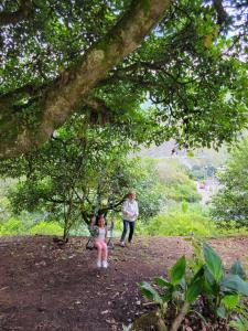 une femme et une petite fille assises sous un arbre dans l'établissement Casa Vacacional Los Guayacanes, à Baños