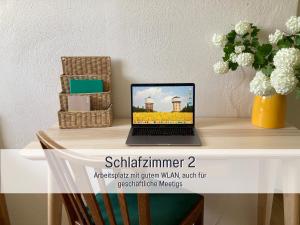 a laptop on a table with a vase of flowers at Ferienwohnung am Maximilianpark Hamm in Hamm