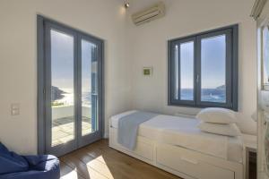 1 dormitorio con paredes y ventanas blancas y 1 cama en Seaside luxury villa, en Ándros