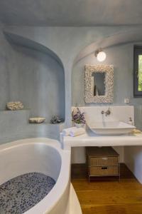 y baño con bañera, lavabo y espejo. en Seaside luxury villa, en Ándros