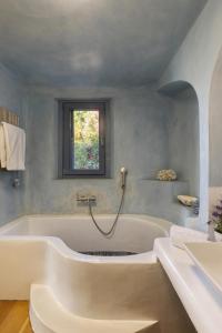 baño con bañera grande y ventana en Seaside luxury villa, en Ándros