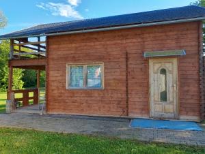 a wooden house with a door and a porch at Chaloupka u potůčku in Damníkov