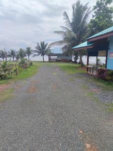 a gravel road next to a building with palm trees at Chuttong resort in Trat