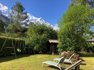 two chairs and a swing in a yard with a mountain at Chalet LE TRIOLET in Chamonix-Mont-Blanc
