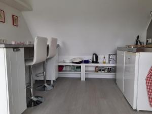 a kitchen with two white chairs and a counter at Spatzennest Löbach in Hennef