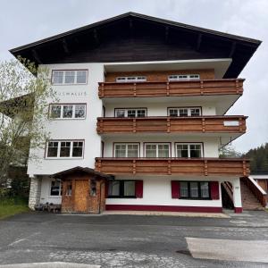 Hillside One - Ski-In Ski-Out Apartments am Arlberg في وارث ام ارلبرغ: مبنى ابيض كبير بسقف خشبي
