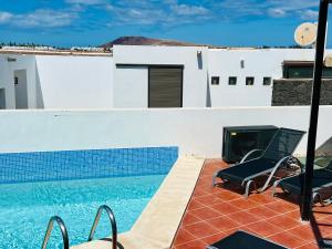 a swimming pool with two chairs and a fireplace at Trendy Villa Isabella, heated pool in Playa Blanca