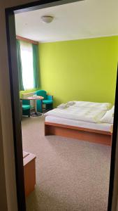 ein Schlafzimmer mit einem Bett und einer grünen Wand in der Unterkunft Grandhotel Nový Bor in Nový Bor