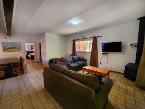 ein Wohnzimmer mit einem Sofa und einem TV in der Unterkunft Pine Valley in Lanseria