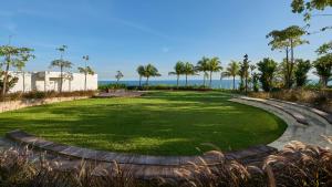 a large grassy area with palm trees and the ocean at Apartemen Borneo Bay City (1 Bedroom Studio) in Klandasan Kecil