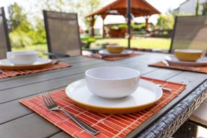 a table with a white bowl and a plate and fork at Kulcsi-Duna Vendégház in Kulcs +29 photos