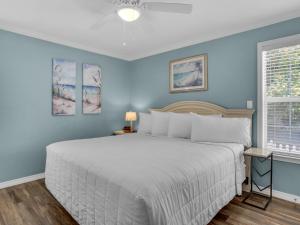 a bedroom with a white bed and blue walls at Cozy Beach House by Newman-Dailey in Destin