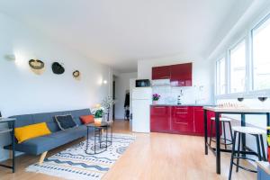 sala de estar con sofá y cocina con armarios rojos. en Syrah - Proche La Défense & Paris, en Nanterre