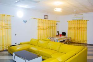 a yellow couch in a living room with yellow curtains at Appartement de Haut Standing à Abomey-Calavi in Abomey-Calavi