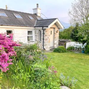 uma casa de pedra com um quintal com flores em Close to Snowdon with Mountain views of Snowdonia em Caernarfon