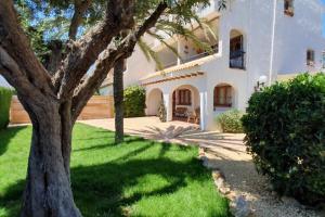 una gran casa blanca con un árbol en el patio en Beautiful apartment with garden El Campello, en El Campello
