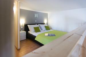 a bedroom with a bed with green and white pillows at Apartments Storia in Trogir