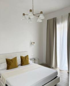 a white bedroom with a large bed with yellow pillows at Sciantusa in Avola