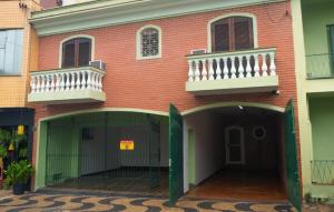 a red brick building with two balconies and a garage at Anexo São João in Piracicaba