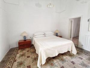 a white bedroom with a bed and two lamps at Domus Donata in Galatone