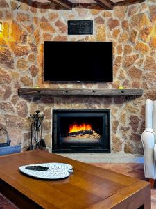 a stone wall with a fireplace with a tv above it at Alojamiento Rural Viña El Labrador in Andújar