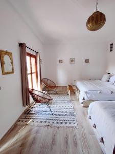 Habitación blanca con 2 camas y ventana en Zagora Oasis Lodge, en Zagora