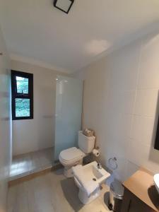 a white bathroom with a toilet and a sink at Alto Chacras Cottage in Chacras de Coria