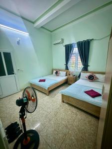 a room with two beds and a fan in it at Minh Huy Hotel in Quang Ninh