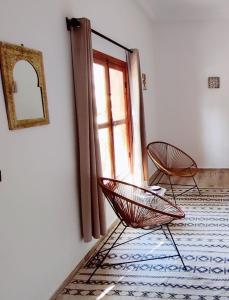 2 chaises assises dans une pièce avec fenêtre dans l'établissement Zagora Oasis Lodge, à Zagora