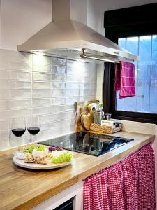 a kitchen with a plate of food and two glasses of wine at Alojamiento Rural Viña El Labrador in Andújar