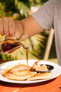 a person pouring syrup onto a plate of pancakes at Soy Local Guatape in Guatapé