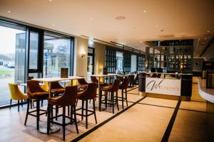un restaurante con mesas, sillas y ventanas en Crow Wood Hotel & Spa Resort en Burnley