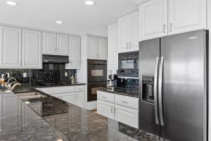 a kitchen with white cabinets and a stainless steel refrigerator at Brighton Adventure in San Diego