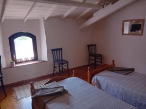 a bedroom with two beds and two chairs and a window at Su Mulinu 