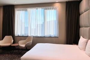 a bedroom with a bed and two chairs and a window at Hotel Levell in Amsterdam