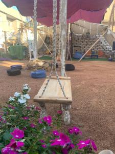 a wooden swing in a garden with flowers at The Way Hostel double Room in Dahab