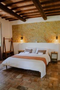 a bedroom with a large bed in a stone wall at Le Dune rooms in Cinigiano