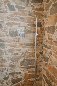 y baño con ducha de piedra y pared de piedra. en Le Dune rooms, en Cinigiano