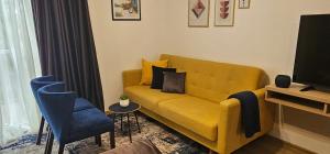 a living room with a yellow couch and a blue chair at Apartmani blue i green in Bugojno
