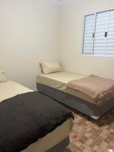 3 Betten in einem Zimmer mit Fenster in der Unterkunft Casa do Monte in Guarulhos