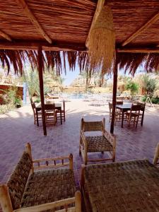 einen Pavillon mit Tischen und Stühlen sowie einem Tisch und Stühlen in der Unterkunft Zagora Oasis Lodge in Zagora