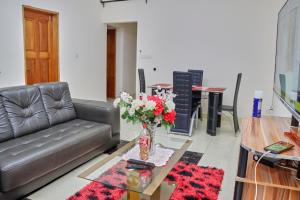 ein Wohnzimmer mit einem Sofa und einem Tisch mit Blumen in der Unterkunft J&B Home in Kribi