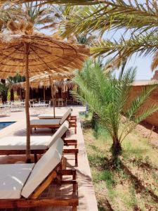eine Gruppe von Stühlen, einem Sonnenschirm und einem Pool in der Unterkunft Zagora Oasis Lodge in Zagora