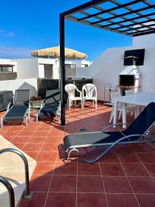 a patio with chairs and tables and a grill at Trendy Villa Isabella in Playa Blanca