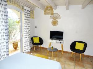 Zimmer mit 2 Stühlen, einem TV und einem Tisch in der Unterkunft Maison de 2 chambres avec piscine partagee terrasse amenagee et wifi a Cardet in Cardet