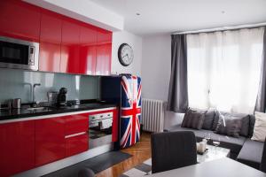 a kitchen with red cabinets and a living room at Apartamento City SOLO ADULTOS in Madrid